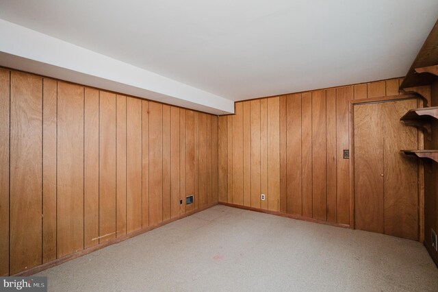 carpeted spare room featuring wood walls