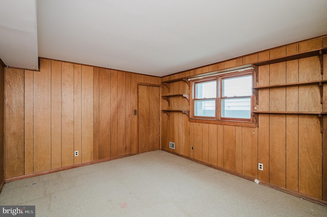 carpeted spare room featuring wooden walls