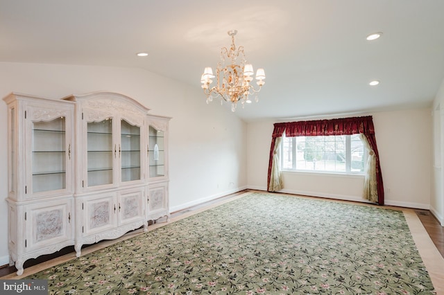 spare room with a chandelier, hardwood / wood-style floors, and vaulted ceiling