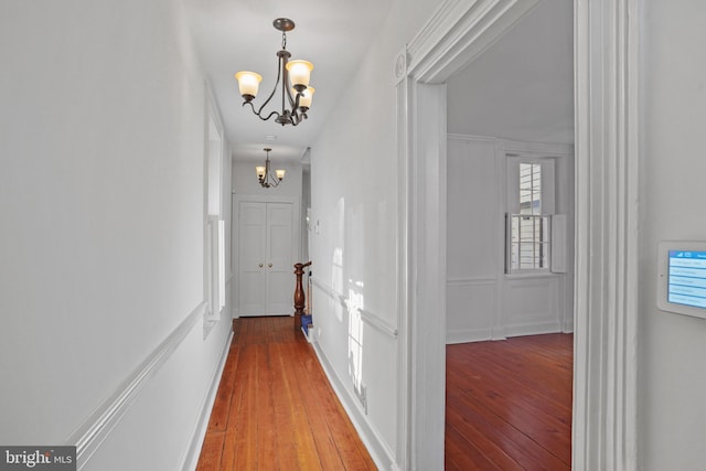 hallway with hardwood / wood-style floors and an inviting chandelier