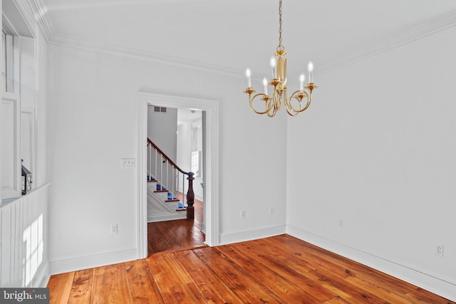 unfurnished room featuring a notable chandelier, hardwood / wood-style flooring, and ornamental molding