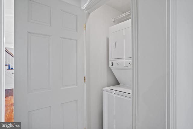 laundry area featuring hardwood / wood-style floors and stacked washing maching and dryer