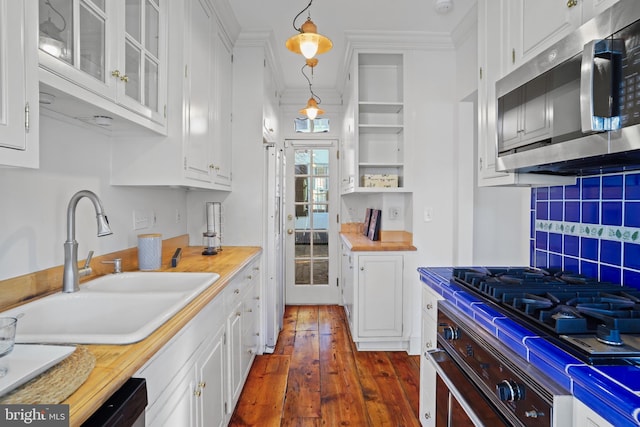 kitchen with stainless steel appliances, white cabinets, and decorative light fixtures