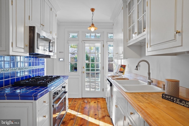 kitchen featuring decorative light fixtures, sink, white cabinets, light hardwood / wood-style floors, and stainless steel appliances