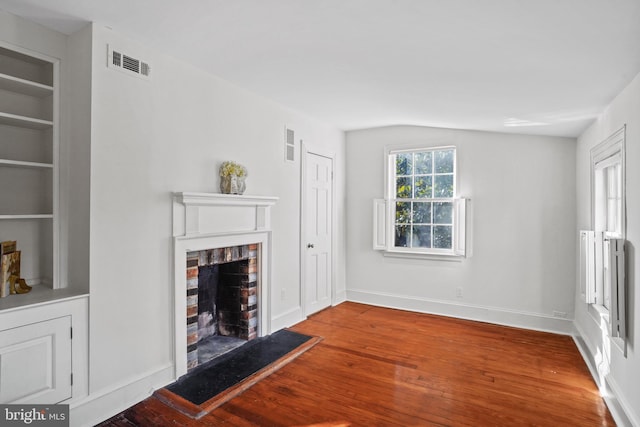 unfurnished living room featuring hardwood / wood-style flooring and a brick fireplace