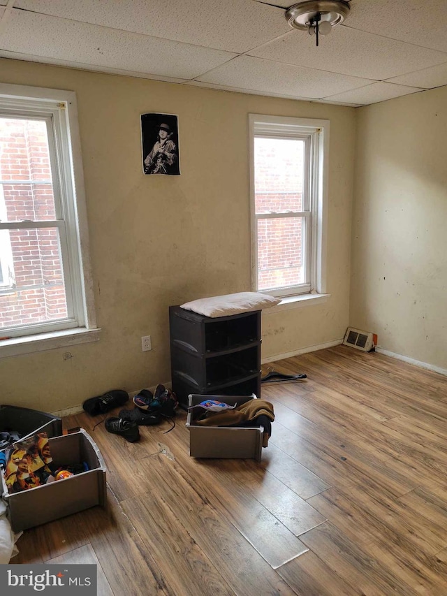 miscellaneous room with a paneled ceiling, hardwood / wood-style floors, and plenty of natural light