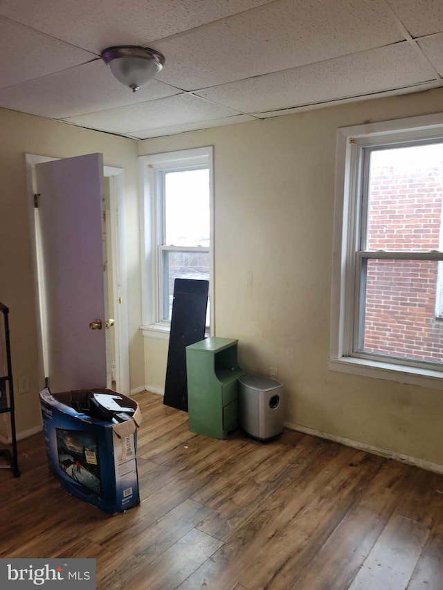 misc room with a paneled ceiling, hardwood / wood-style flooring, and a healthy amount of sunlight