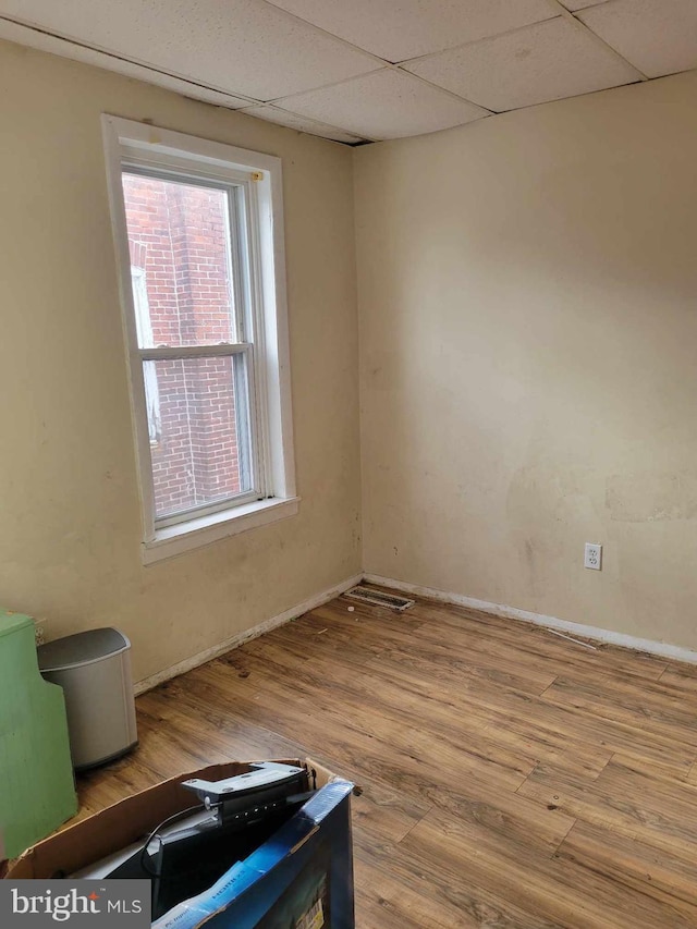 empty room featuring a drop ceiling and wood-type flooring