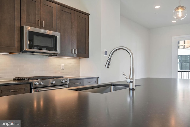 kitchen with tasteful backsplash, dark brown cabinets, appliances with stainless steel finishes, sink, and decorative light fixtures