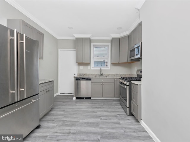 kitchen featuring sink, ornamental molding, gray cabinets, stainless steel appliances, and light stone countertops