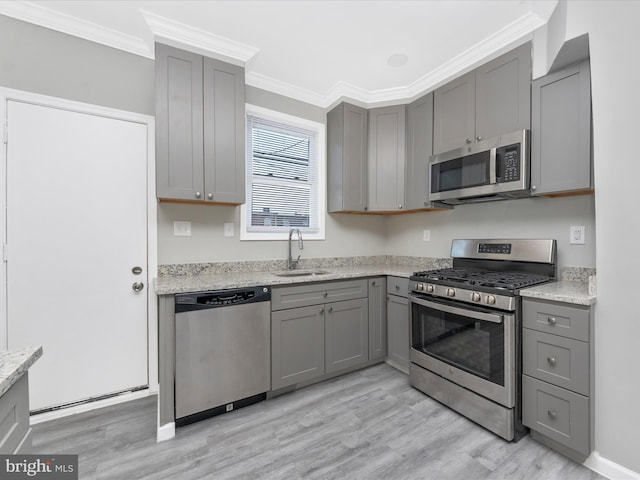 kitchen with stainless steel appliances, crown molding, light stone countertops, and gray cabinets