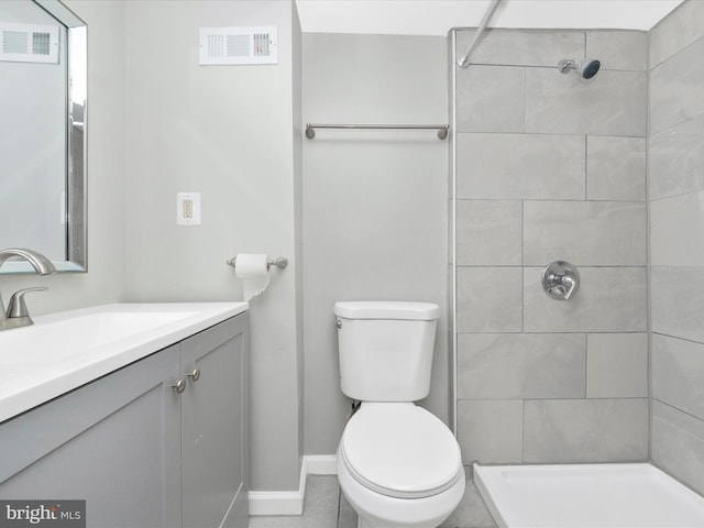 bathroom featuring vanity, toilet, and a tile shower