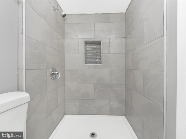 bathroom featuring tiled shower and toilet