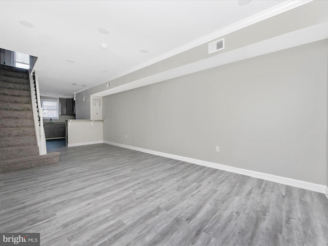 unfurnished living room featuring crown molding and hardwood / wood-style floors