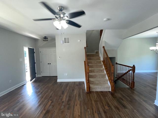 staircase with wood-type flooring and ceiling fan with notable chandelier