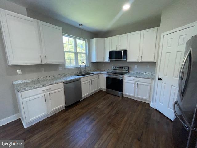 kitchen featuring sink, white cabinetry, stainless steel appliances, and dark wood-type flooring