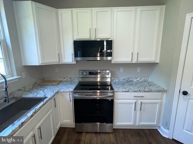 kitchen with dark hardwood / wood-style flooring, sink, white cabinets, and appliances with stainless steel finishes