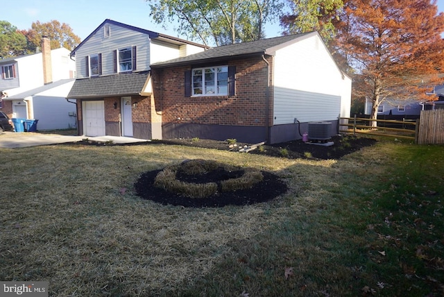 view of front of house with central AC unit, a garage, and a front lawn