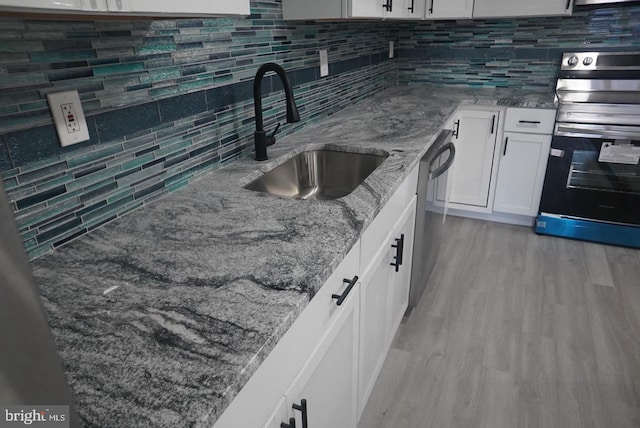 kitchen featuring sink, light stone countertops, tasteful backsplash, white cabinetry, and stainless steel appliances