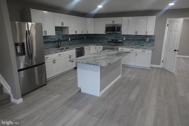 kitchen with light stone counters, sink, white cabinetry, and stainless steel appliances