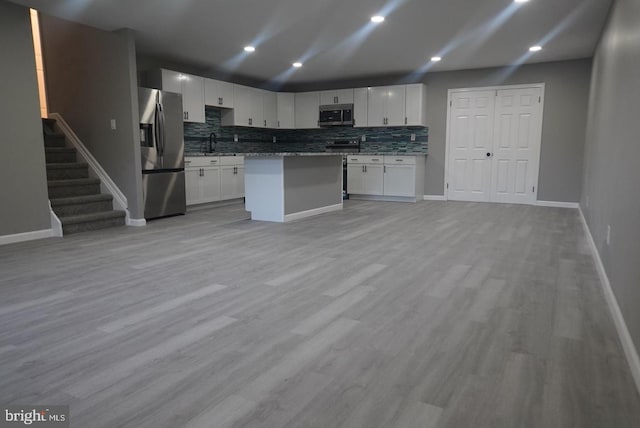 kitchen with white cabinets, sink, light hardwood / wood-style flooring, appliances with stainless steel finishes, and a kitchen island