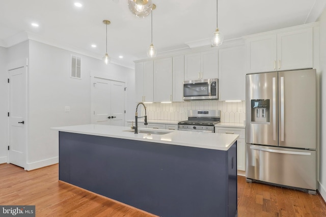 kitchen featuring white cabinetry, stainless steel appliances, sink, and an island with sink