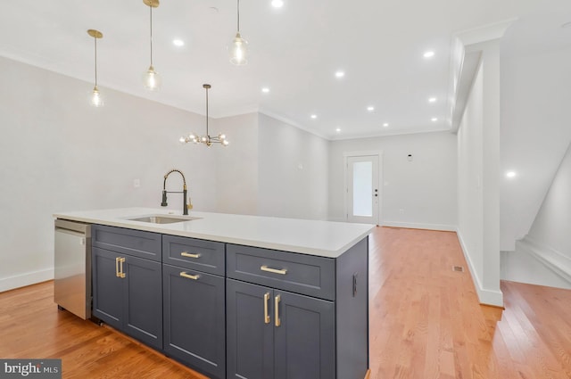 kitchen with an island with sink, stainless steel dishwasher, light wood-type flooring, sink, and decorative light fixtures