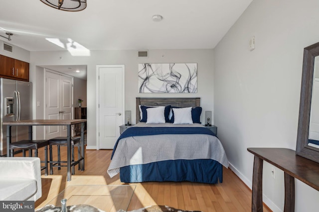 bedroom featuring light hardwood / wood-style flooring and stainless steel fridge