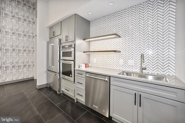 kitchen with stainless steel appliances, gray cabinets, dark tile patterned floors, and sink