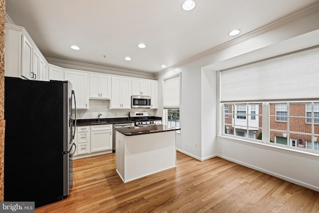 kitchen with white cabinets, light hardwood / wood-style flooring, a kitchen island, and stainless steel appliances