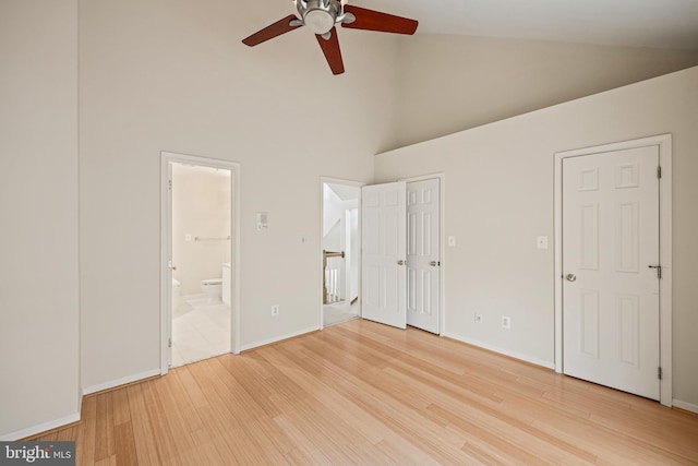 unfurnished bedroom featuring wood-type flooring, connected bathroom, high vaulted ceiling, and ceiling fan