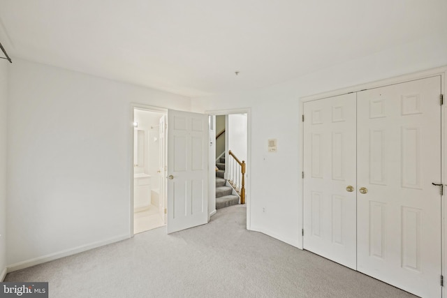 unfurnished bedroom with ensuite bathroom, light colored carpet, and a closet