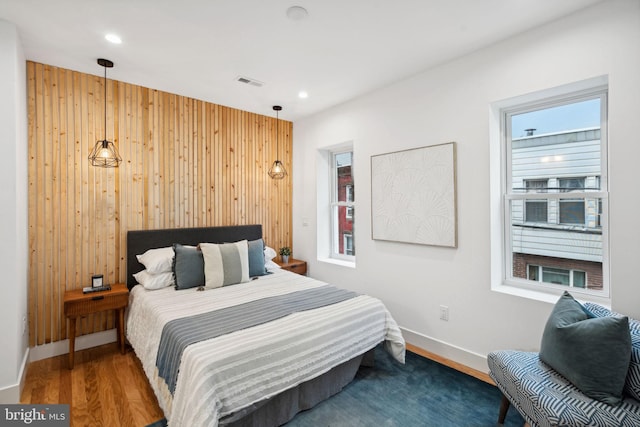 bedroom with hardwood / wood-style flooring and wood walls