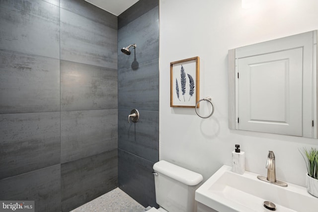 bathroom with vanity, tiled shower, and toilet