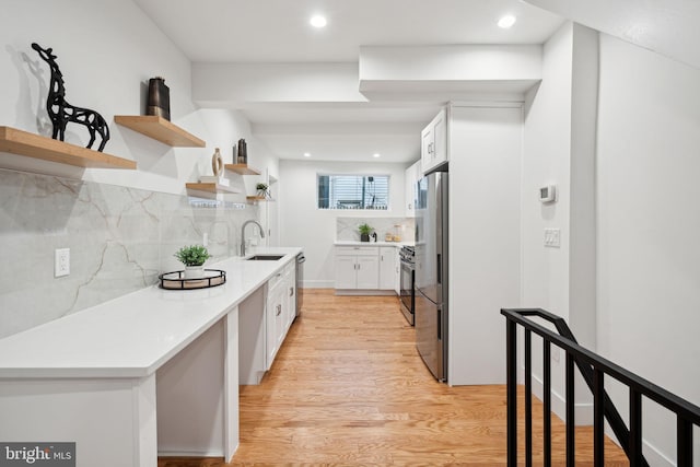 kitchen with sink, white cabinetry, light hardwood / wood-style floors, and tasteful backsplash