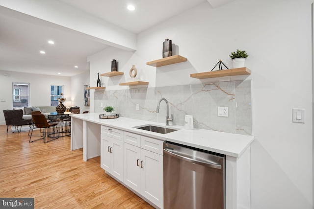 kitchen featuring decorative backsplash, white cabinets, light hardwood / wood-style flooring, dishwasher, and sink