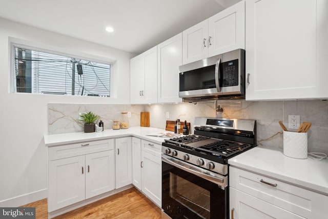 kitchen featuring decorative backsplash, white cabinets, stainless steel appliances, and light wood-type flooring