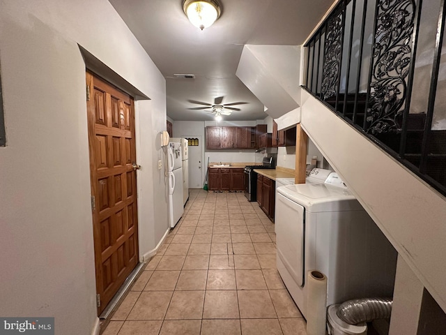 kitchen featuring washer / dryer, light tile patterned flooring, white refrigerator, stainless steel range with gas stovetop, and ceiling fan