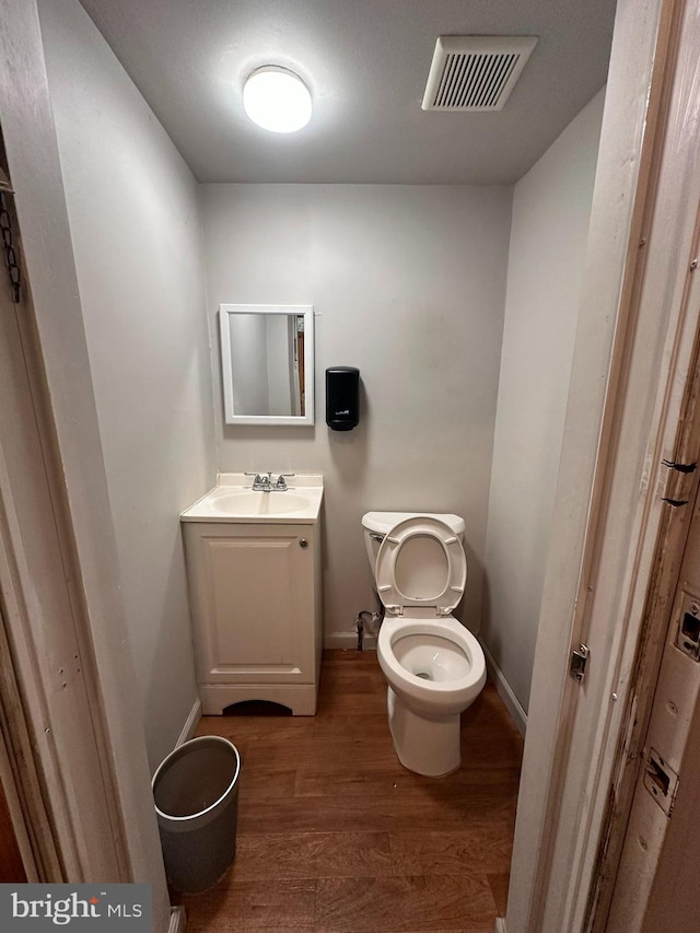 bathroom with vanity, toilet, and hardwood / wood-style flooring