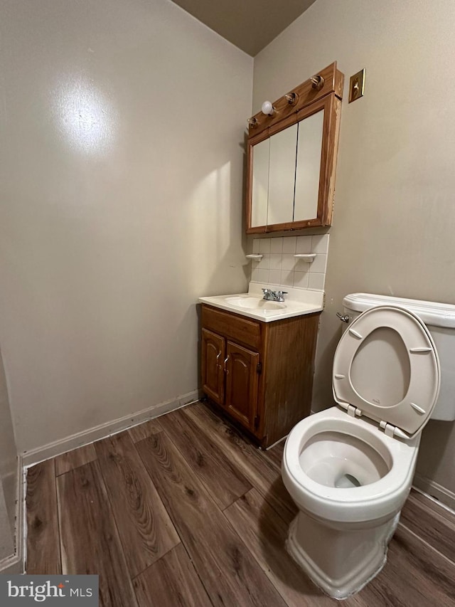 bathroom with toilet, tasteful backsplash, vanity, and wood-type flooring