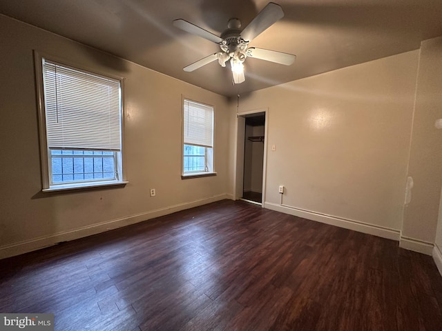 unfurnished bedroom with multiple windows, a closet, dark wood-type flooring, and ceiling fan