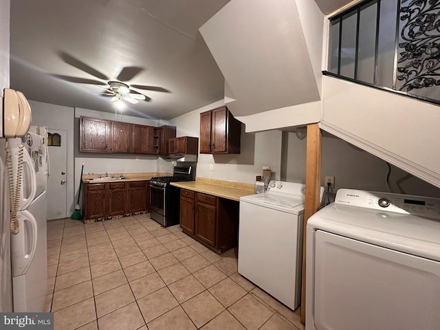 kitchen featuring washer and clothes dryer, stainless steel gas stove, sink, light tile patterned floors, and white fridge