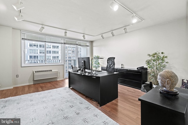 office space featuring wood-type flooring, a wall mounted air conditioner, and track lighting