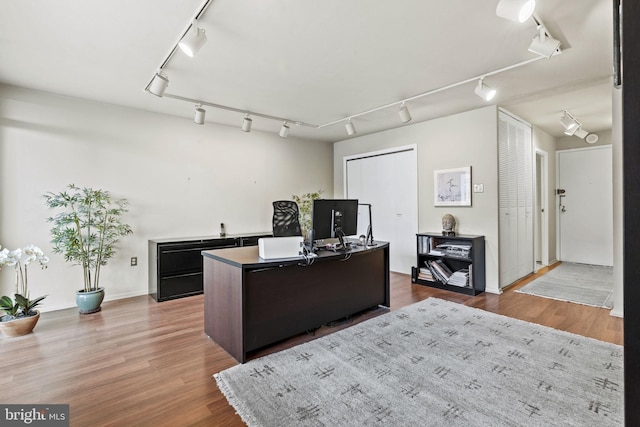 home office with hardwood / wood-style flooring and track lighting