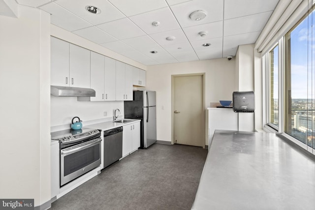 kitchen with concrete floors, white cabinetry, appliances with stainless steel finishes, a paneled ceiling, and sink