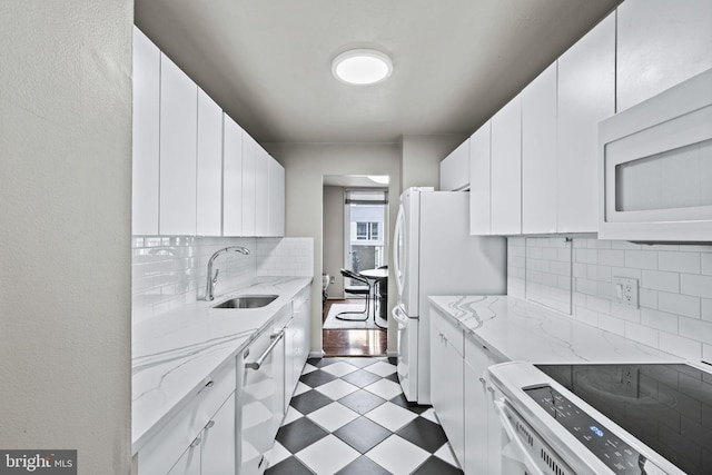 kitchen featuring light stone countertops, white appliances, white cabinetry, and sink