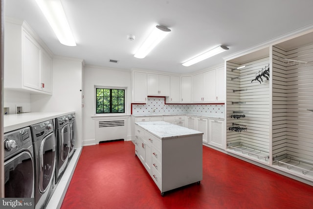 kitchen featuring washing machine and dryer, a center island, white cabinets, light stone counters, and decorative backsplash