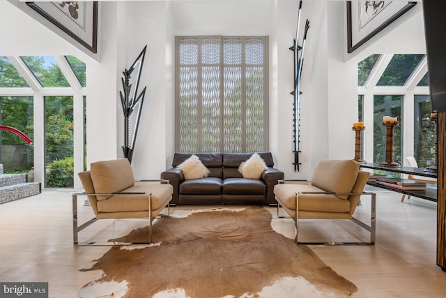 sitting room with a high ceiling and light hardwood / wood-style floors