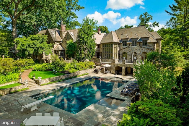 view of swimming pool featuring a diving board and a patio