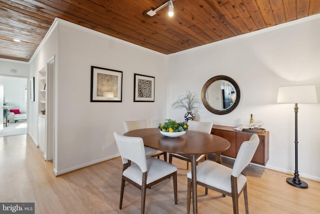 dining area featuring rail lighting, ornamental molding, light hardwood / wood-style floors, built in shelves, and wooden ceiling